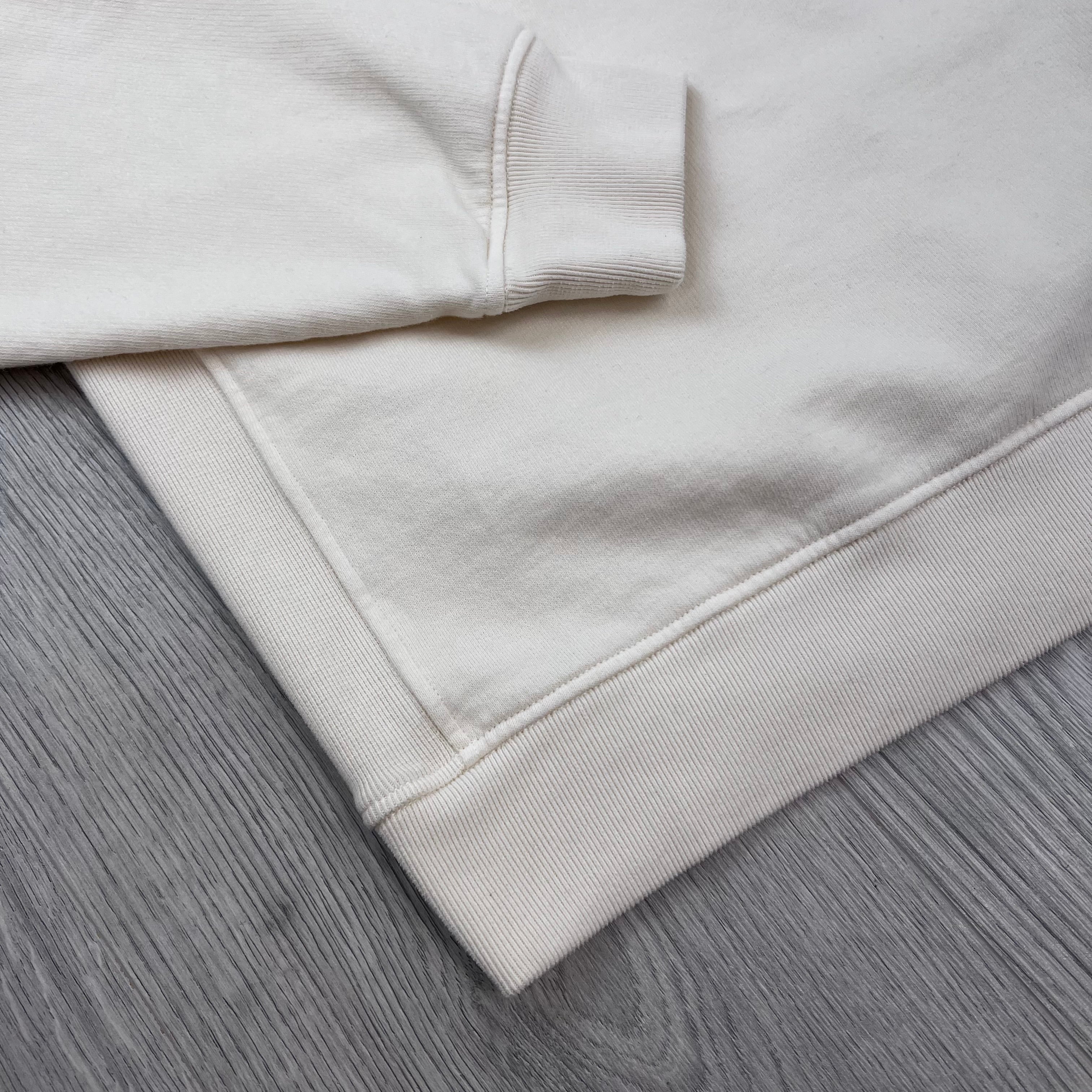 A close up view of the cuffs and hem on a Stone Island Crewneck Brushed Cotton Sweatshirt in Ivory.