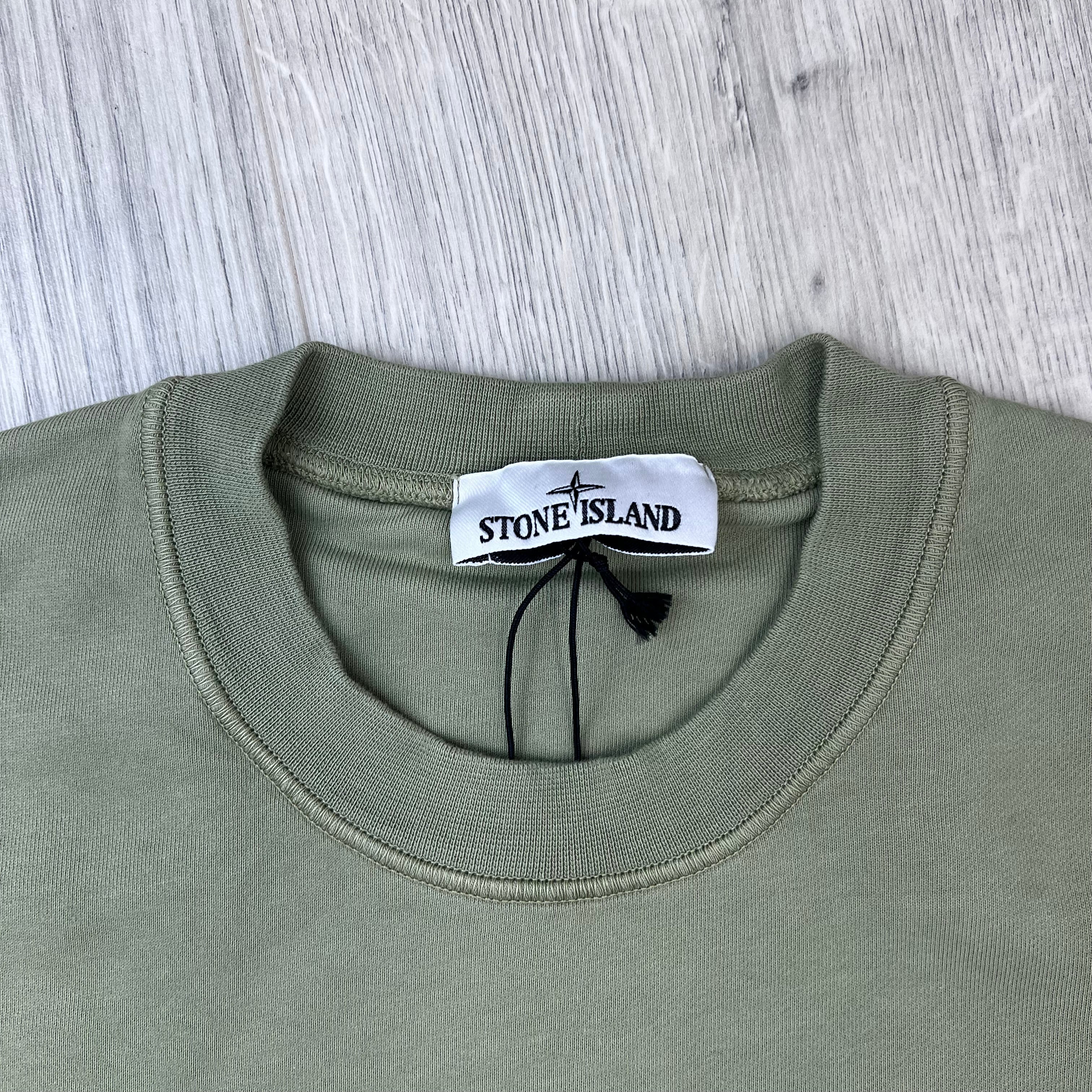 A close up view of the crewneck and label on a Stone Island Crewneck Sweatshirt in Laurel Green.